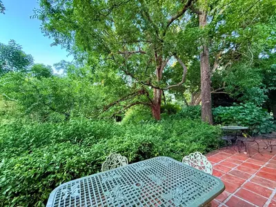 a table and chairs on a brick patio with trees at Die Jonkmanshuis in Stellenbosch