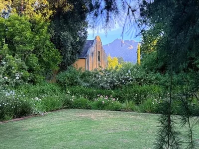 a garden with flowers and a church in the background at Die Jonkmanshuis in Stellenbosch