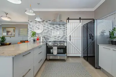 a kitchen with white cabinets and a clock on the wall at 75 on Chapman in Gordonʼs Bay
