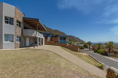 a house on a hill with the ocean in the background at 75 on Chapman in Gordonʼs Bay