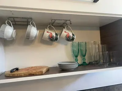 a shelf with plates and glasses and utensils at Studio Seabiscuit in Cape Town