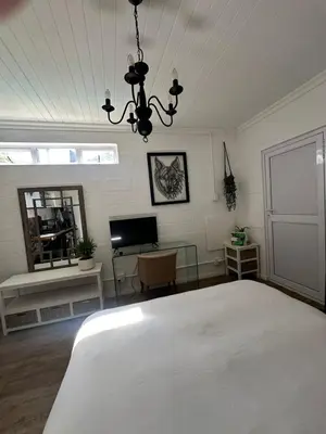 a bedroom with a white bed and a chandelier at Studio Seabiscuit in Cape Town