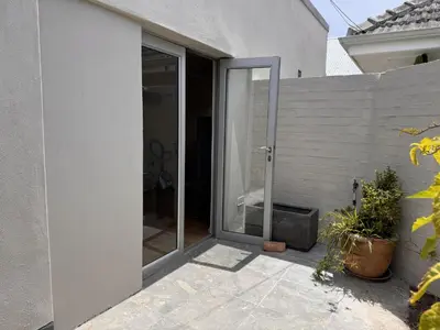 a sliding glass door in a white house at Mimosa Cottage in Cape Town