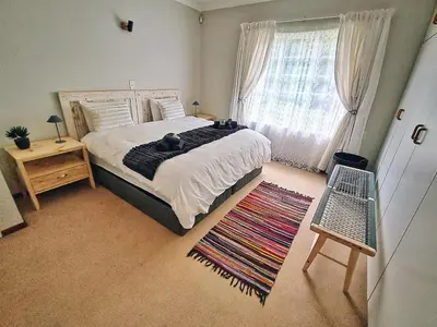 a bedroom with a bed and a window and a rug at Swannie Creek in Grabouw