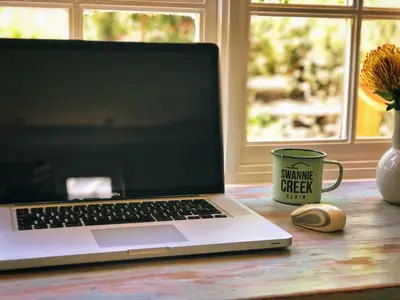a laptop computer sitting on a table next to a coffee mug at Swannie Creek in Grabouw