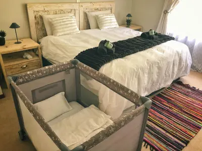 a bedroom with a large bed with a crib at Swannie Creek in Grabouw