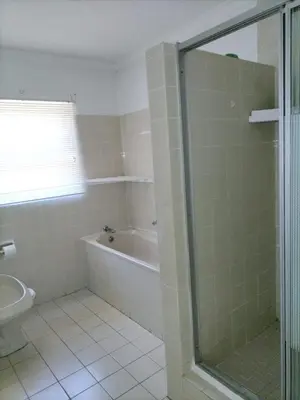 a bathroom with a shower and a tub and a toilet at The Garden House in Hermanus