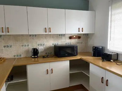 a kitchen with white cabinets and a microwave on a counter at The Garden House in Hermanus