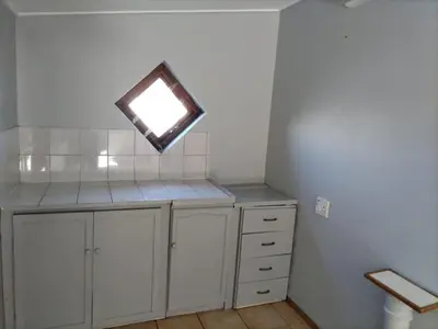 a small kitchen with a window and a white cabinet at The Garden House in Hermanus