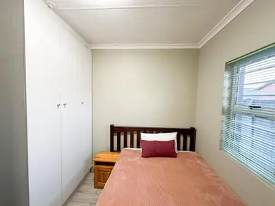a bedroom with a bed with a red pillow on it at 29 on Windsor-2 Bedroom House in Silver Sands