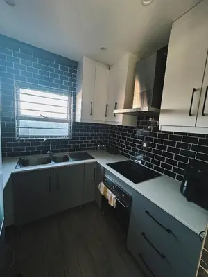 a kitchen with white cabinets and a sink and a stove at 29 on Windsor-2 Bedroom House in Silver Sands