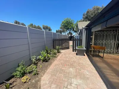 a fence with a bench next to a brick sidewalk at Vynhubia in Monte Vista