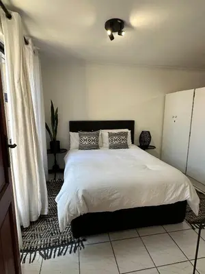 a bedroom with a large bed with white sheets at A Stone's Throw away in Cape Town
