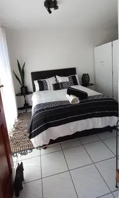 a bedroom with a bed with a black and white blanket at A Stone's Throw away in Cape Town