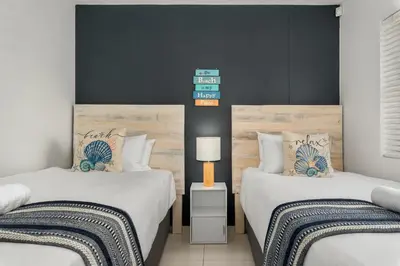 a bedroom with two beds and a lamp on a table at La Cabina 105 in Cape Town