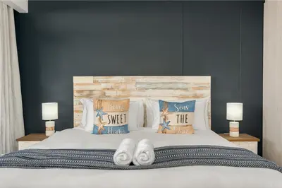 a bedroom with a bed with white sheets and pillows at La Cabina 105 in Cape Town