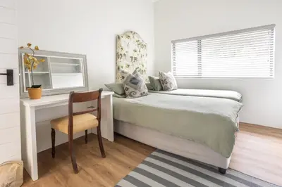 a bedroom with a bed and a desk and a window at 5 Bedroom Family Home with Private Apartment in Hermanus