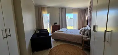 a bedroom with a bed and a chair and a window at Kite Surfers Haven in Cape Town