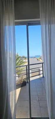 a view of the beach from a balcony with curtains at Kite Surfers Haven in Cape Town