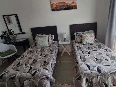 a bedroom with two twin beds and a table at Grey Vine Cottage - Flatlet in Cape Town
