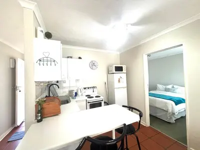 a room with a kitchen with a bed and a table at 111 Hermanus beach club in Hermanus