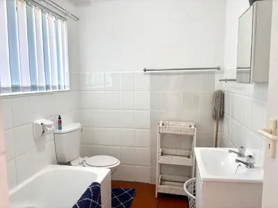 a white bathroom with a toilet and a sink at 111 Hermanus beach club in Hermanus