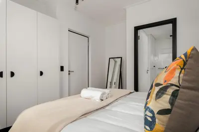 a bedroom with white walls and a bed with a mirror at Nine Palms Stunning 1-Bedroom Apartment in Century City