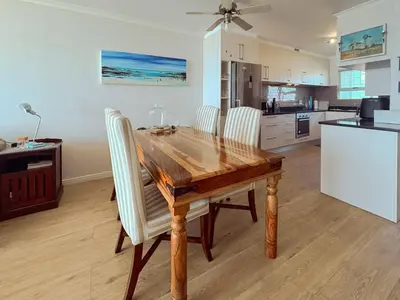 a dining room table with chairs and a kitchen at 510 Odeon Towers - SeaView in Strand