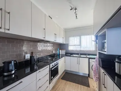 a kitchen with white cabinets and black counter tops at 510 Odeon Towers - SeaView in Strand