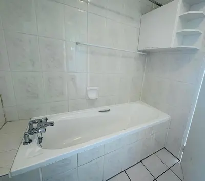 a white bath tub in a white tiled bathroom at 510 Odeon Towers - SeaView in Strand