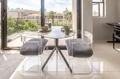 a glass table and two chairs in a room with a balcony at St Tropez On Lake 302 The Island Club in Cape Town