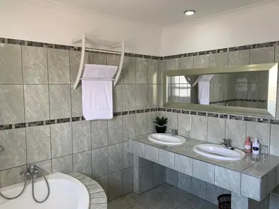 a bathroom with two sinks and a mirror and a tub at Carmel Huys in Cape Town
