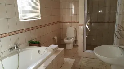 a bathroom with a tub and a toilet and a sink at Carmel Huys in Cape Town