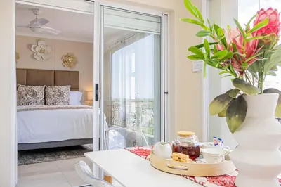 a room with a bed and a table with a vase at Bella View in Cape Town