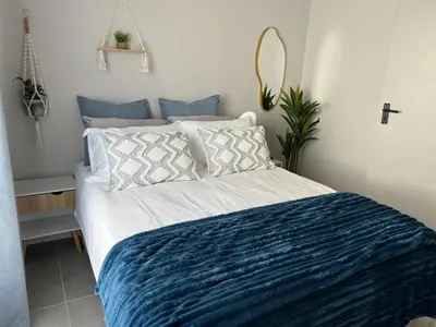 a bedroom with a bed with a blue and white comforter at Rissie's Villa in Gordonʼs Bay