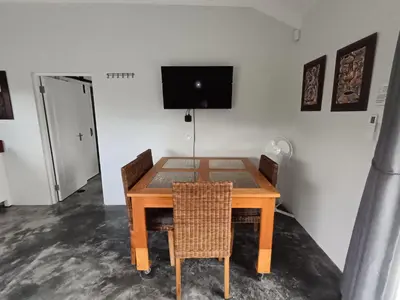 a dining room table with chairs and a television on the wall at 66onjennings Strand in Strand