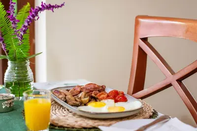 a plate of breakfast food on a table with orange juice at 5 Seasons Guest House in Stellenbosch