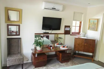a living room with a desk and a tv at 5 Seasons Guest House in Stellenbosch