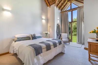 a bedroom with a bed and a large window at Farm House with Pool & Never Ending Mountain Views in Stellenbosch