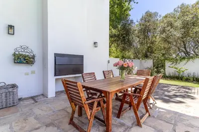 a wooden table with chairs and a vase of flowers at Farm House with Pool & Never Ending Mountain Views in Stellenbosch