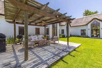 a patio with a wooden pergola and a grill at Farm House with Pool & Never Ending Mountain Views in Stellenbosch