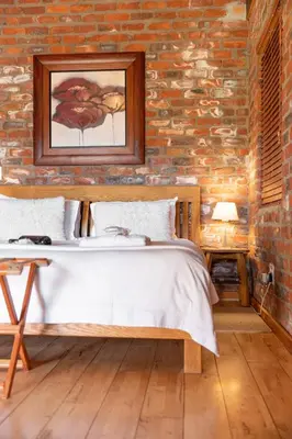 a bedroom with a bed and a brick wall at Lovane Boutique Wine Estate and Guesthouse in Stellenbosch