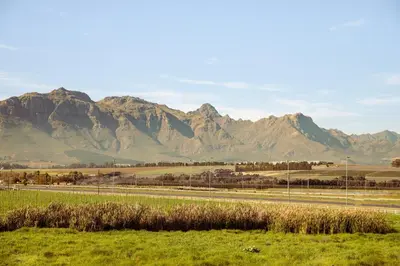 a road with a mountain range in the background at Lovane Boutique Wine Estate and Guesthouse in Stellenbosch
