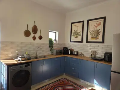 a kitchen with blue cabinets and a washing machine at Swallows Nest Garden Cottage in Helderberg