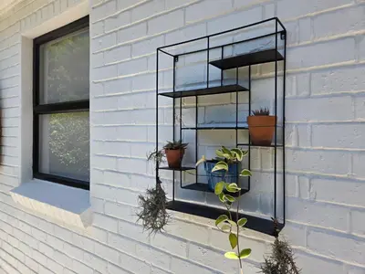 a black shelf with potted plants on a wall at Swallows Nest Garden Cottage in Helderberg