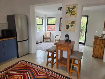 a kitchen with a table and a refrigerator at Swallows Nest Garden Cottage in Helderberg