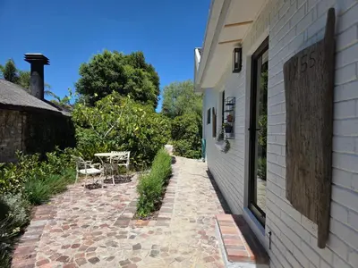 a brick walkway next to a building with a table at Swallows Nest Garden Cottage in Helderberg