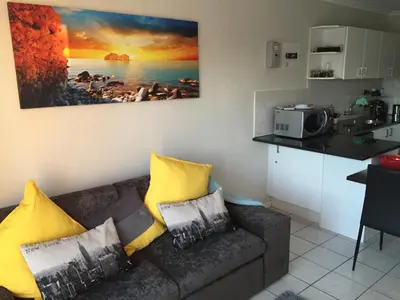 a living room with a couch and a kitchen at 10 South Views in Bloubergstrand