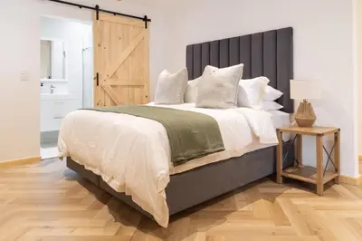 a bedroom with a large bed with a wooden headboard at Villa Noor Modern 2 Bed Luxury Retreat in Hanover Park