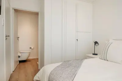 a white bedroom with a bed and a bath tub at Hermanus Beach Club 218 in Hermanus